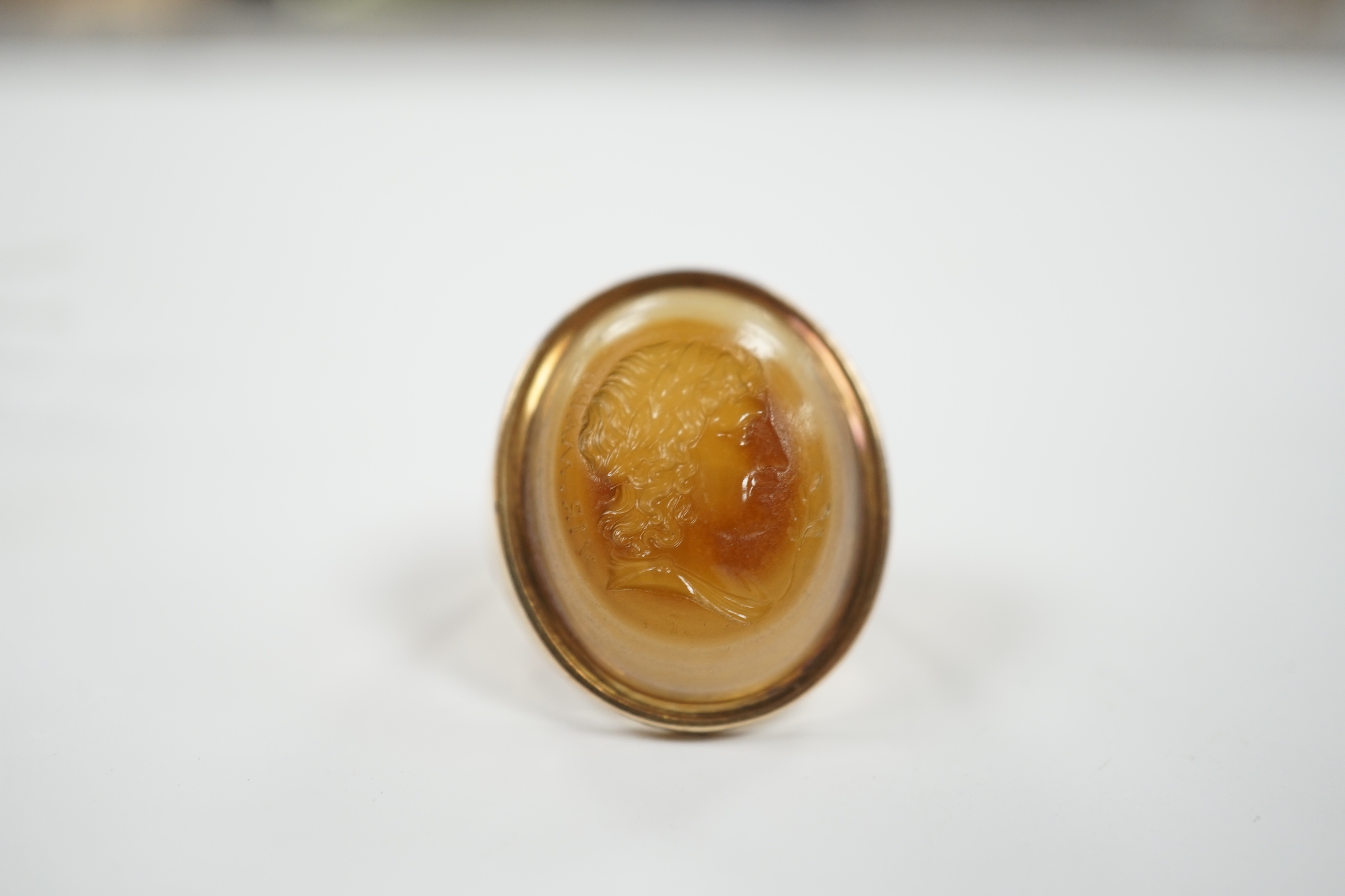 An early 20th century yellow metal and banded agate intaglio ring, carved with the head of a gentleman to sinister, size L, gross weight 8.1 grams.